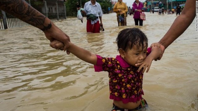 TOPSHOT - Residents hold onto a child as they walk through floodwaters in the Bago region, some 68 km away from Yangon, on July 29, 2018. - Heavy monsoon rains have pounded Karen state, Mon state and Bago region in recent days and show no sign of abating, raising fears that the worst might be yet to come. (Photo by Ye Aung THU / AFP)        (Photo credit should read YE AUNG THU/AFP/Getty Images)